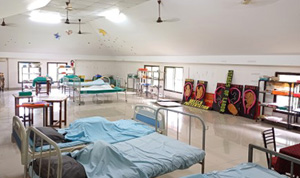 Spacious nursing skills lab with rows of plastic chairs, hospital beds, and training manikins under ceiling fans.