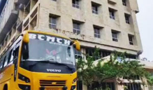 Two-story brick building with arched windows, surrounded by tropical foliage and a grassy courtyard.